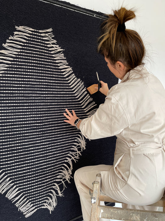 Rombo Black handwoven wool tapestry shown hanging on a wall