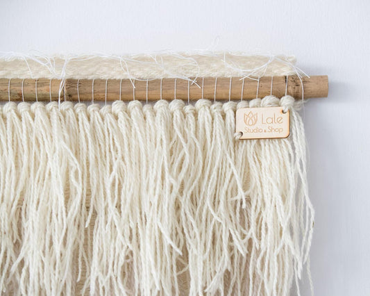 Nude handwoven wool tapestry shown hanging on a wall