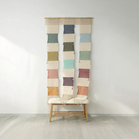 Handwoven Bieno wall tapestry featuring colorful woven squares and fringe details, suspended on a bamboo rod, perfect for boho and eclectic interiors.