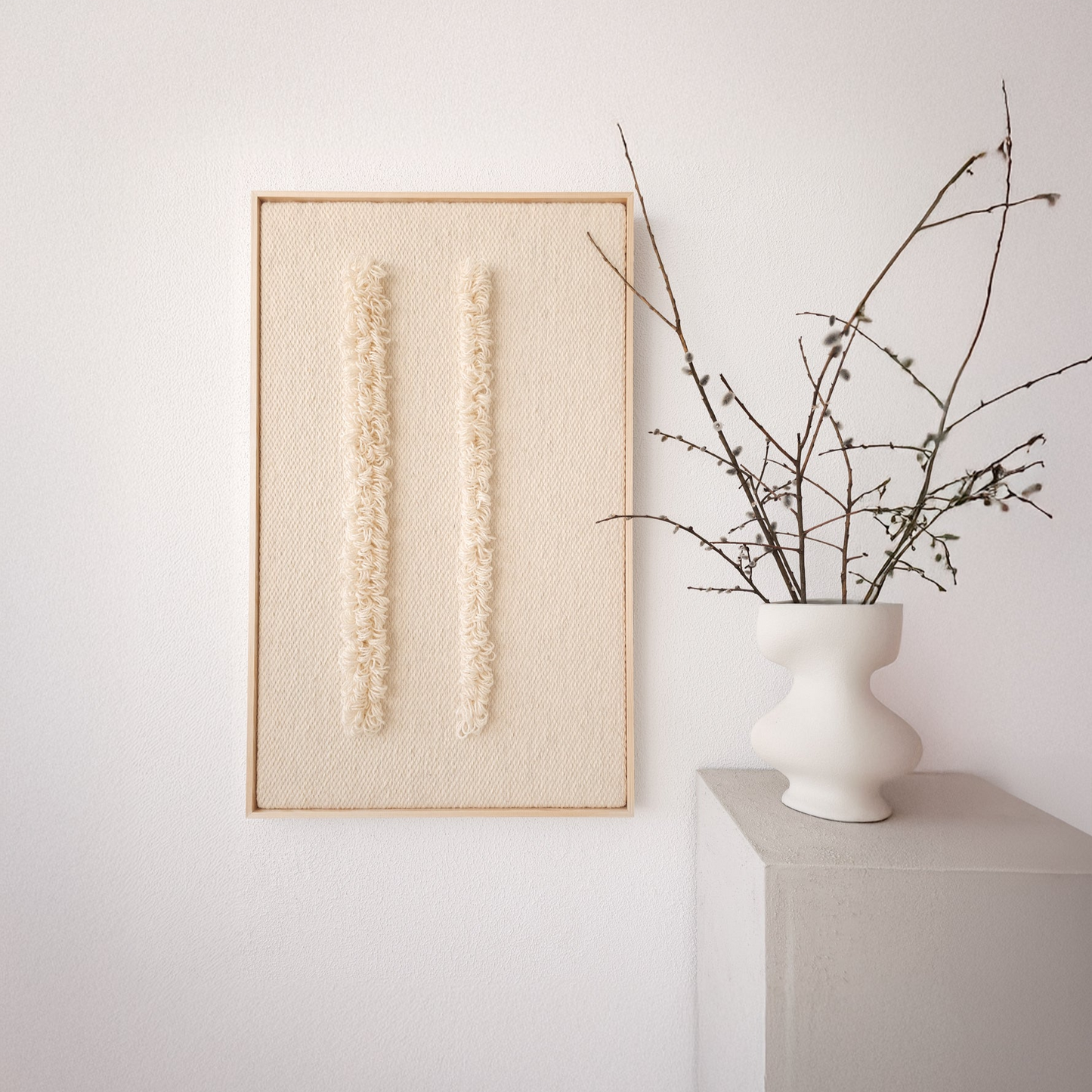 Framed handwoven tapestry with two vertical textured patterns in neutral tones, displayed next to a minimalist white vase, ideal for modern and minimalist interiors.