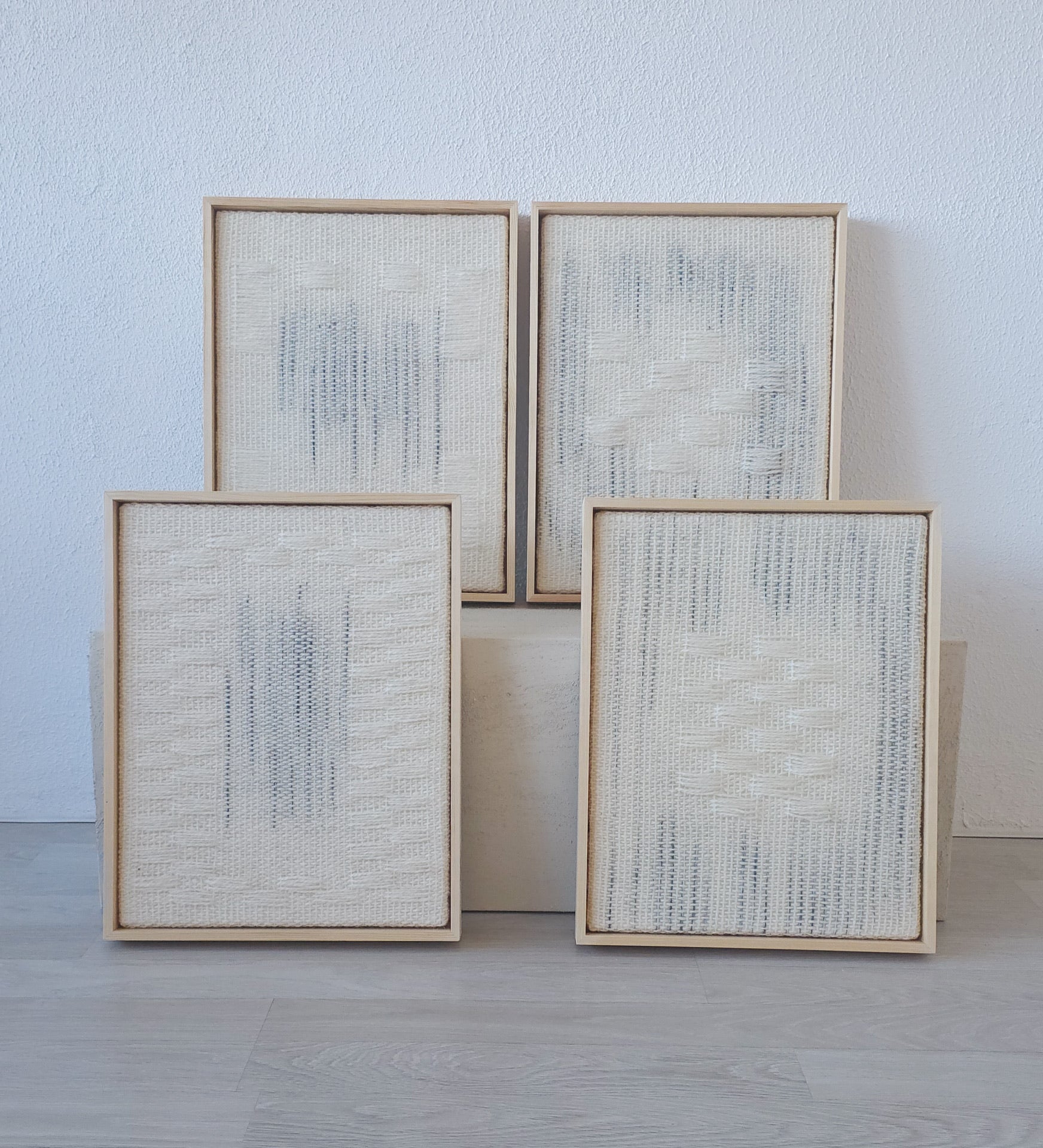 Set of four framed handwoven tapestries in neutral tones with minimalist patterns, displayed together on a textured platform, perfect for modern and Japandi-style interiors.