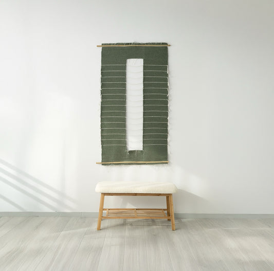 Salvia wall tapestry in bottle green tones, handwoven with natural wool and mounted on a bamboo rod, perfect for minimalist and modern interior design.