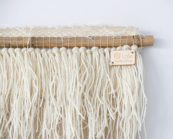 Nude handwoven wool tapestry shown hanging on a wall