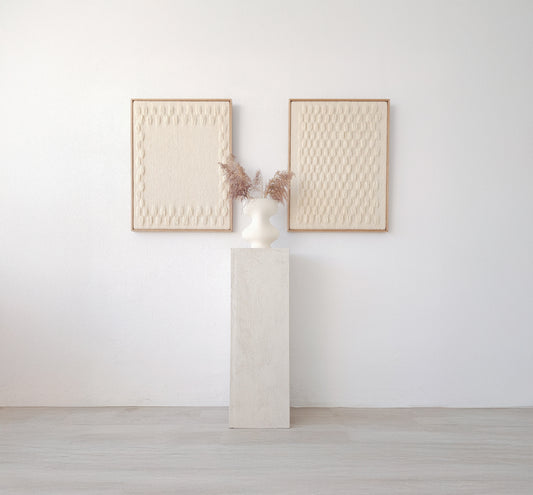 Set of two handcrafted minimalist wall hangings in neutral tones, framed in natural wood, displayed with a modern vase on a pedestal.