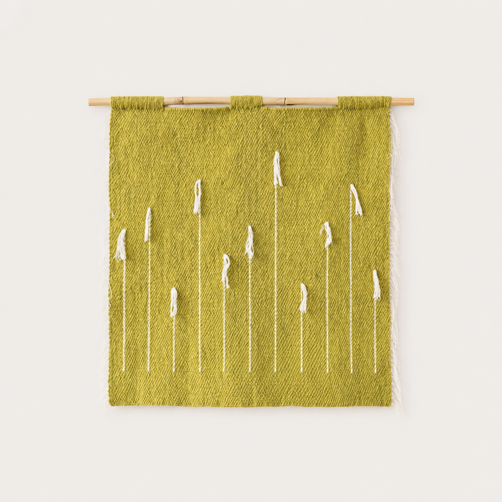 Green Denti di Leone handwoven olive wool wall hanging with white dandelion motif on bamboo rod, packshot, Lale Studio & Shop