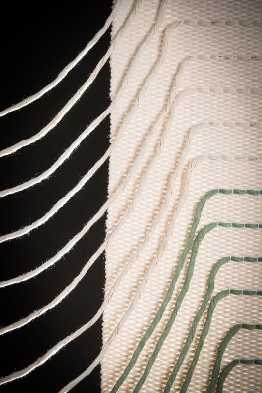 Green Urania handwoven cotton tapestry shown hanging on a wall