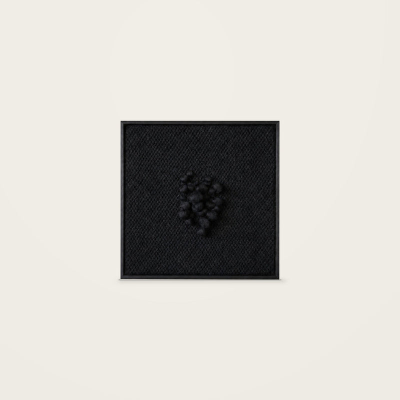 Enigma — black handwoven wool tapestry with raised central texture in a black wooden frame, front view.
