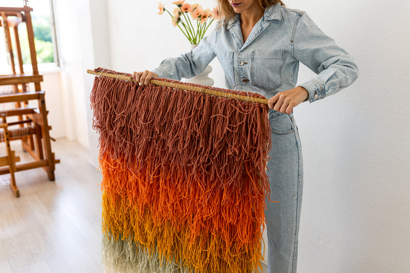 Gerbena wall hanging held by the maker, showing the deep shaggy wool fringe in a warm ombre — handwoven textile art by Lale Studio & Shop