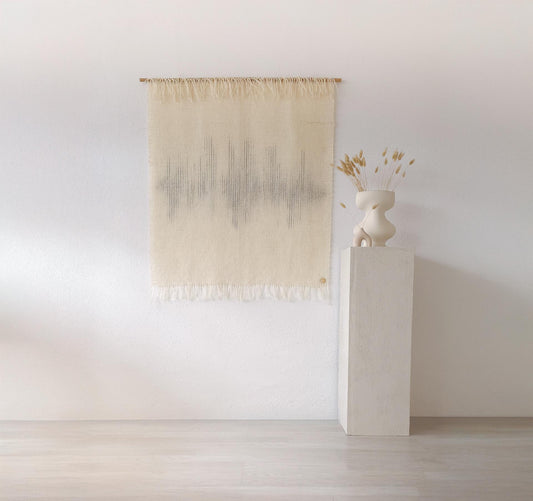 Handwoven wool wall tapestry with a minimalist soundwave-inspired design in natural beige and gray tones, displayed on a bamboo rod against a clean white wall, perfect for modern boho or Japandi-style interiors.