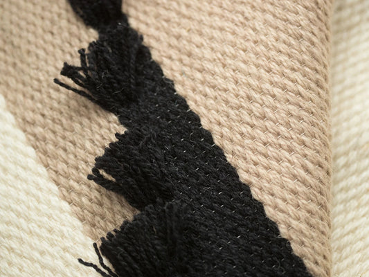 Auroa handwoven wool tapestry shown hanging on a wall