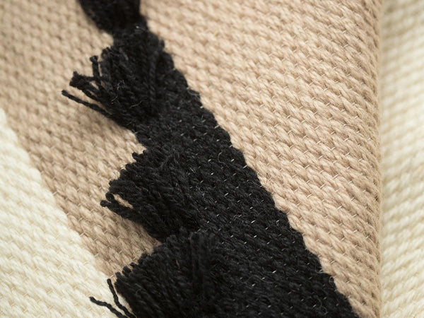 Auroa handwoven wool tapestry shown hanging on a wall