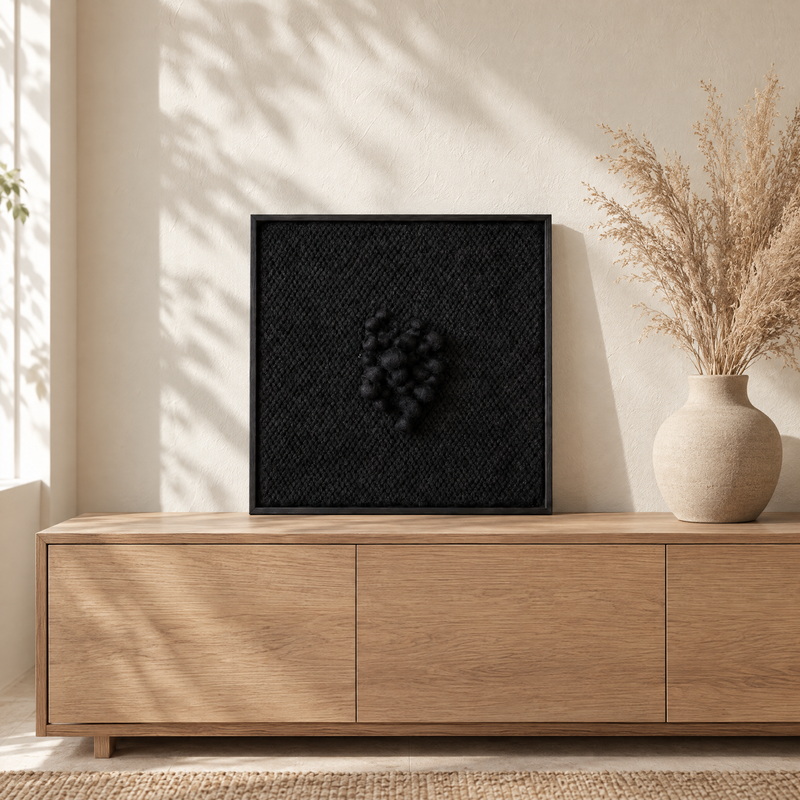 Enigma black sculptural handwoven wool tapestry standing on an oak sideboard in a bright interior, Lale Studio Shop