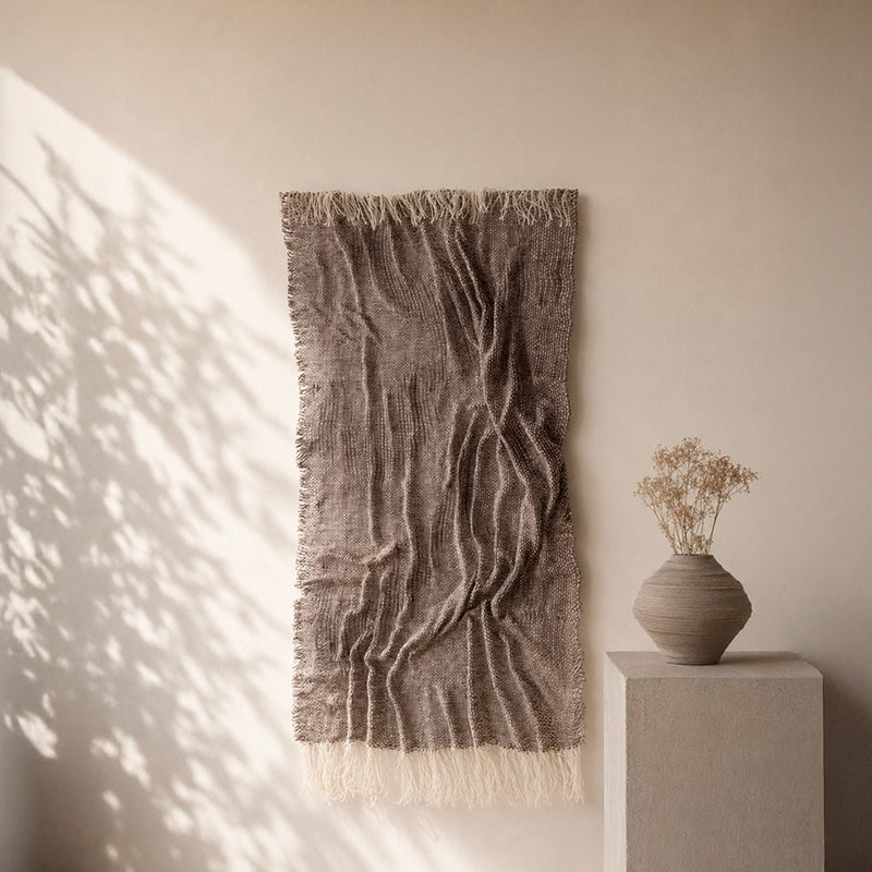 Lutum handwoven wool relief in earth tones from the Aera collection on a plaster wall, Lale Studio & Shop
