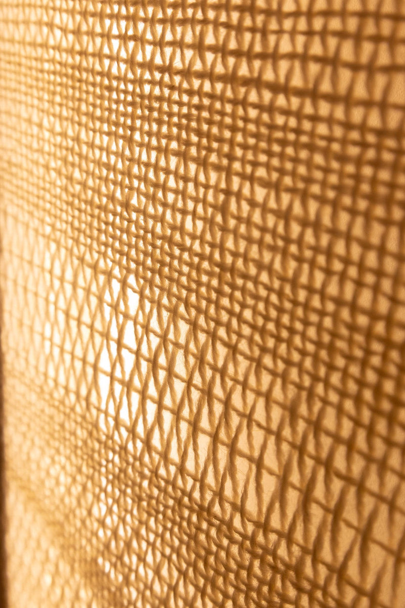 Macro photograph of the irregular handwoven wool pattern illuminated from behind