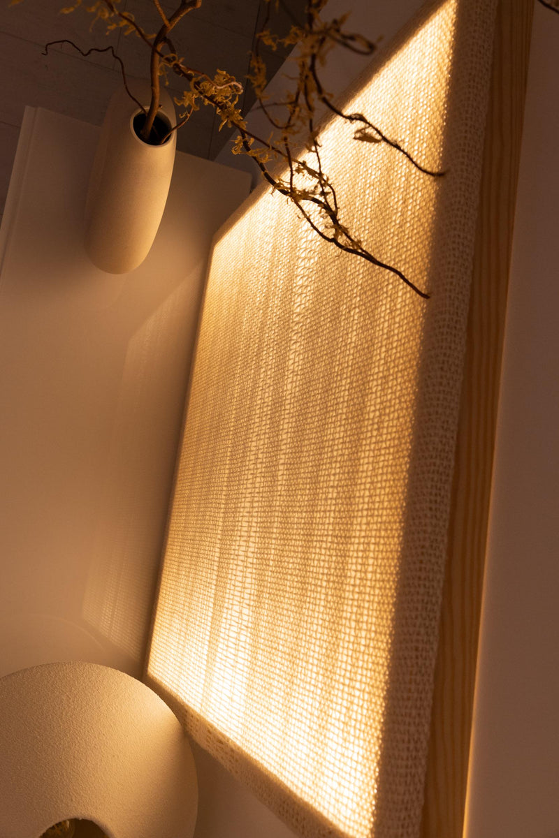 Side view of the illuminated tapestry showing the natural pine frame, depth and open backed construction