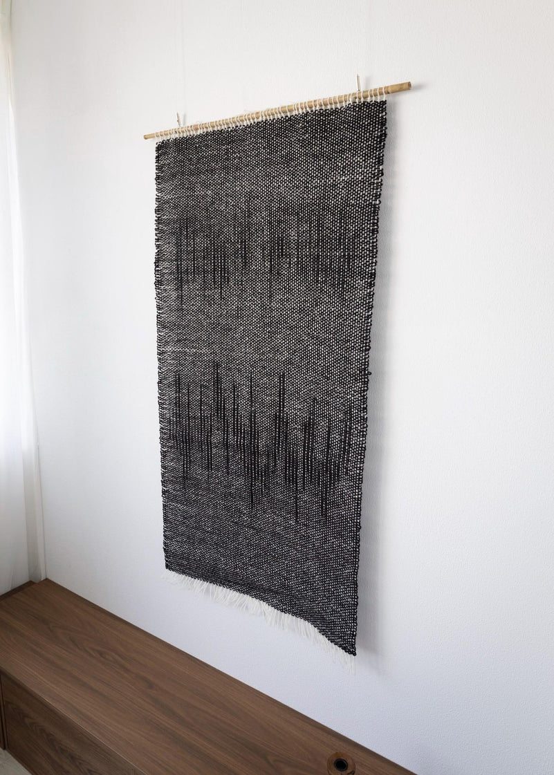 Nyora on its slim bamboo rod with soft cotton fringe — handwoven wool wall hanging by Lale Studio & Shop