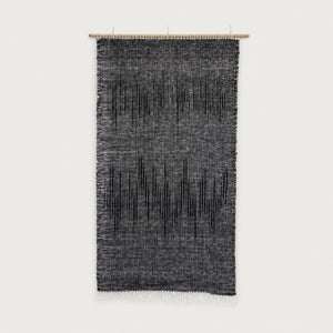 Nyora handwoven two-ply wool tapestry in charcoal and black with a dripping vertical pattern on a slim bamboo rod, minimalist Japandi textile wall art by Lale Studio & Shop