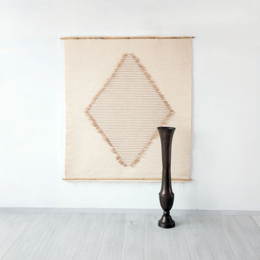 Handwoven Rombo tapestry with a striking diamond pattern in natural wool and beige tones, accented with delicate fringes. A perfect centerpiece for modern and boho-inspired interiors.