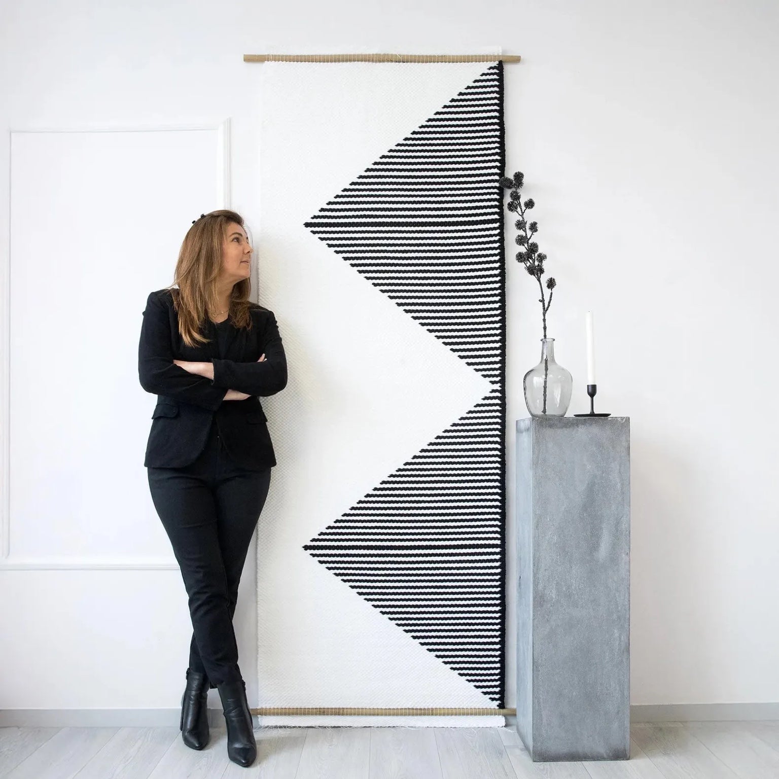 Trian handwoven wall tapestry with a striking black and white geometric triangle design, crafted from premium natural fibers, styled in a modern interior by Lale Studio.